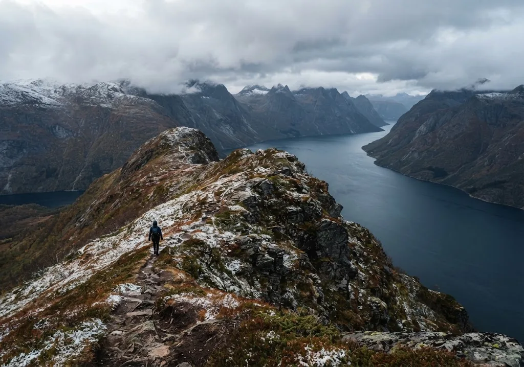 Artist's impression of a hiker on a rocky ridge high above a fjord